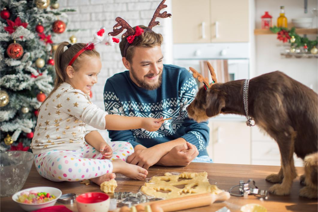 Father and daughter in kitchen for christmas with their dog.