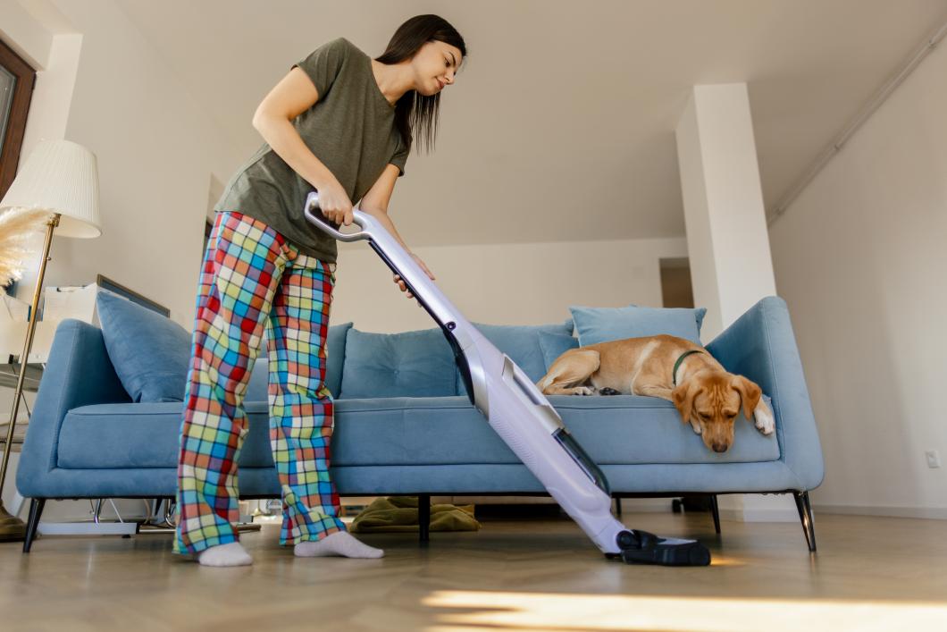 Pet parent vaccuuming floor.